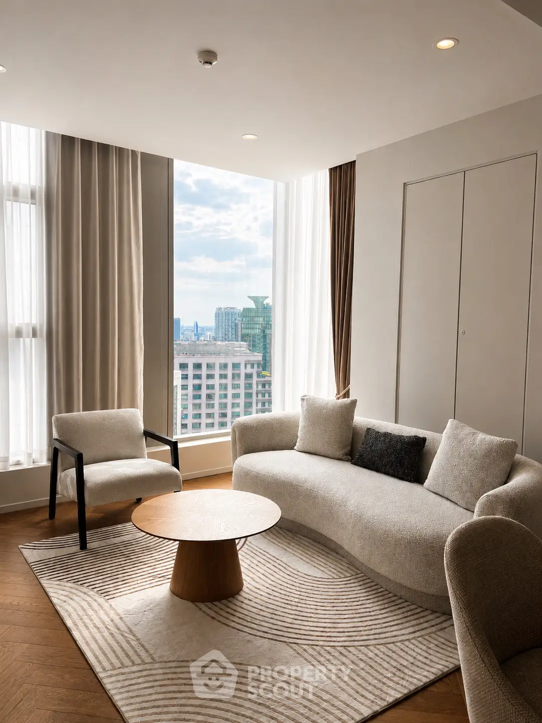 Elegant living room with modern furniture and stunning city view through large windows.