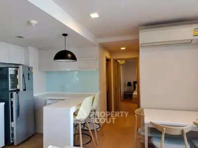 Modern kitchen with open layout and dining area, featuring sleek appliances and stylish lighting.