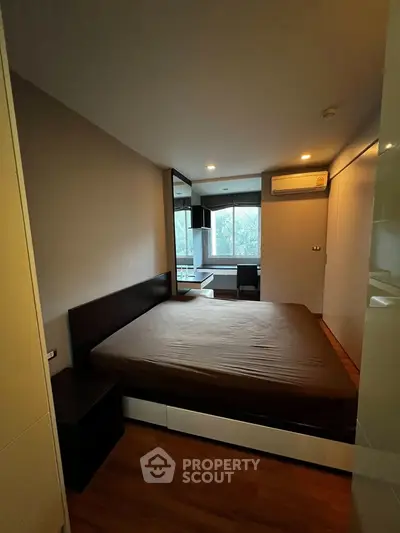 Modern bedroom with large window and built-in storage in a stylish apartment.