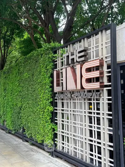 Modern condominium entrance with lush greenery and stylish signage at The Line Phahon-Pradipat.