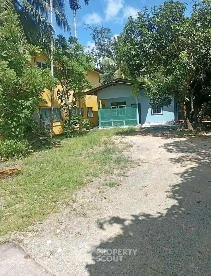 Charming tropical property with lush greenery and colorful buildings under a clear blue sky.