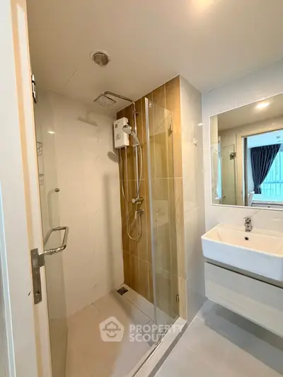 Modern bathroom with glass shower and sleek sink in contemporary apartment.