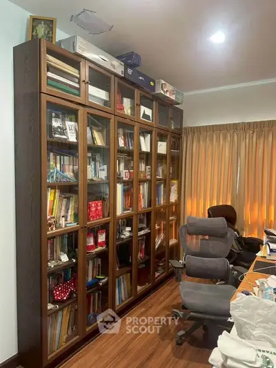 Spacious study room with large wooden bookshelf and comfortable office chairs.