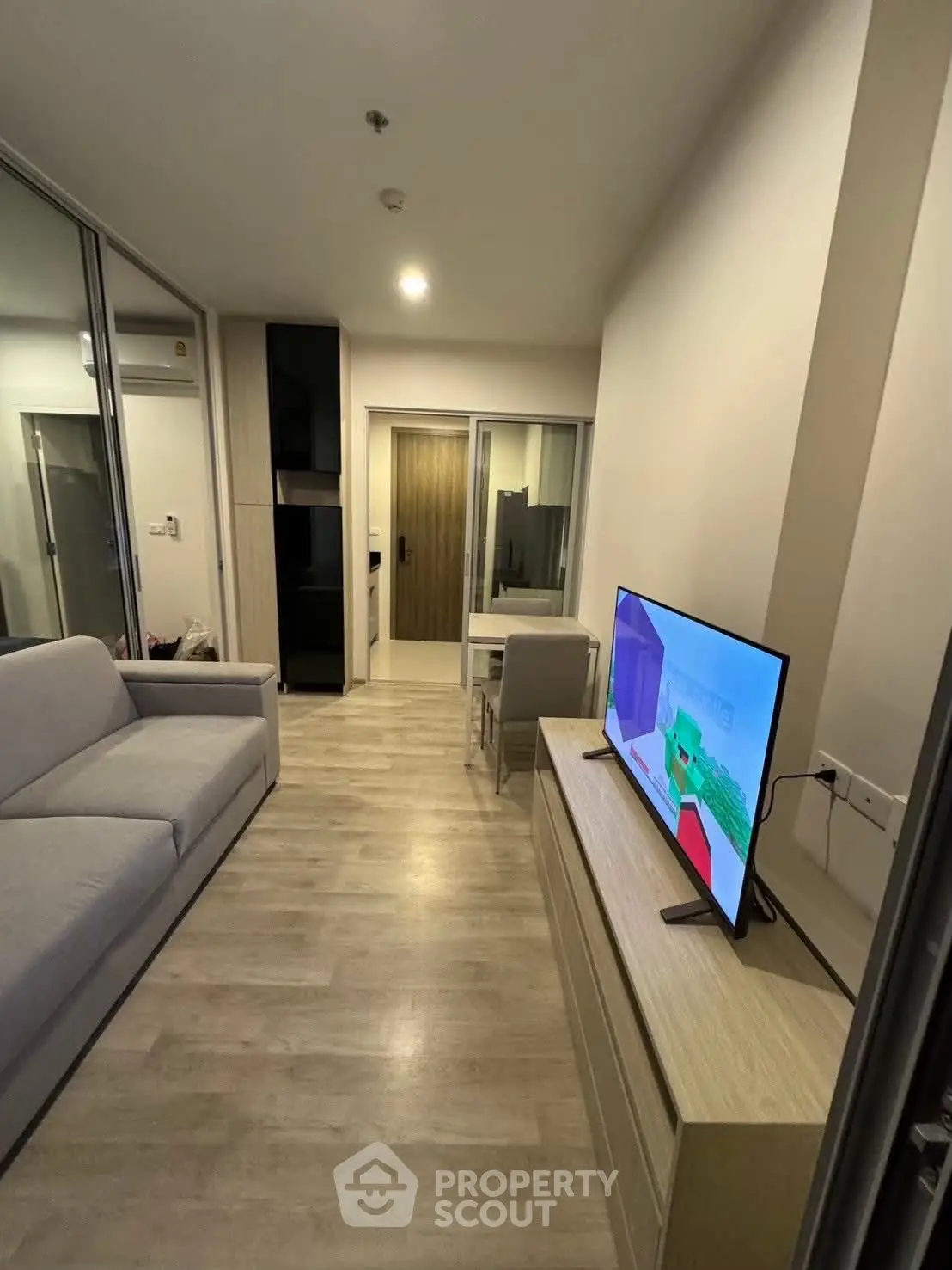 Modern living room with sleek furniture and wall-mounted TV in a cozy apartment.