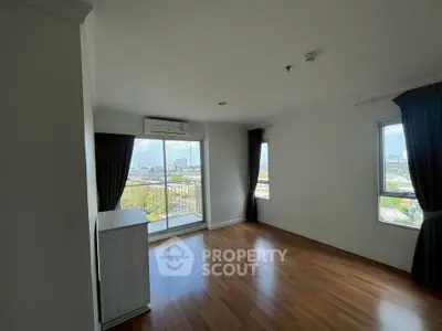 Spacious living room with large windows and balcony offering stunning city views.