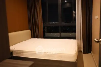 Modern bedroom with large window offering stunning city night view.