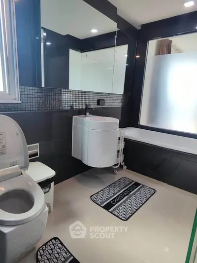 Modern bathroom with sleek black tiles and contemporary fixtures, featuring a bathtub and stylish vanity.