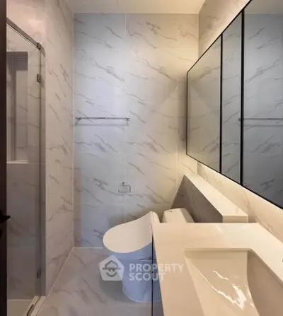 Modern bathroom with sleek design and marble tiles, featuring a stylish toilet and vanity.