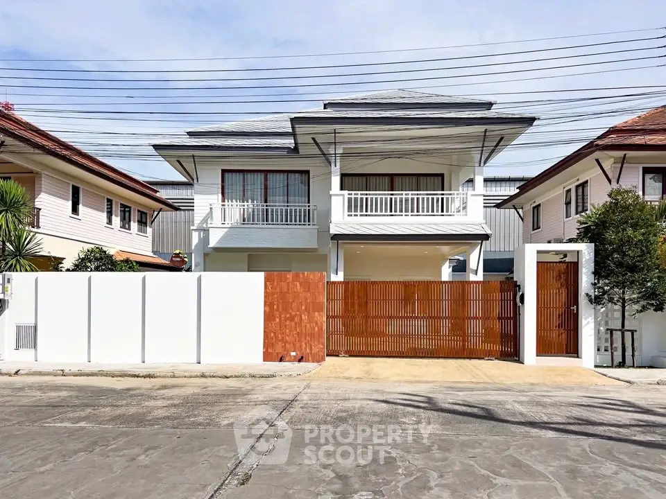 Stunning modern two-story house with a spacious balcony and elegant wooden gate.