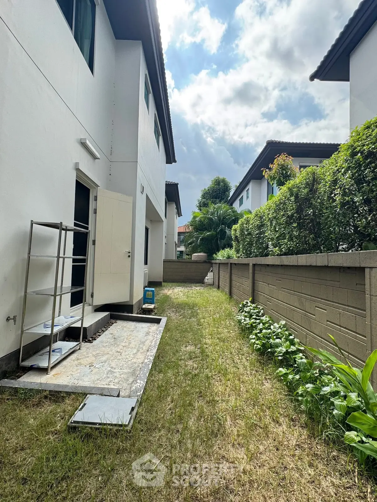 Charming side yard with lush greenery and modern exterior, perfect for outdoor relaxation.
