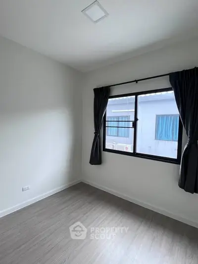 Bright empty room with large window and elegant dark curtains, perfect for customization.