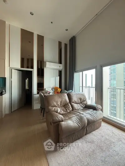 Spacious living room with high ceiling and large windows in modern apartment