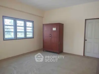 Spacious empty room with large window and wooden wardrobe, perfect for customization.