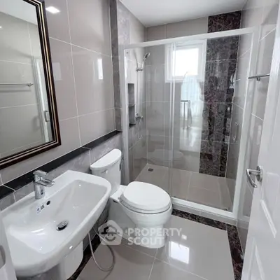 Modern bathroom with sleek fixtures and glass shower enclosure.