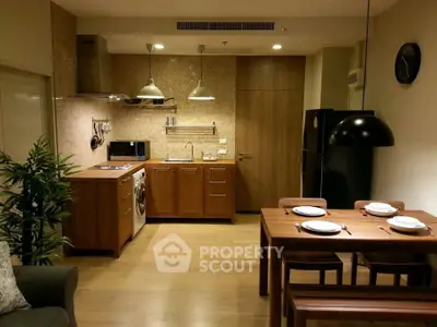 Modern kitchen with wooden cabinets, dining table, and washing machine in cozy apartment.