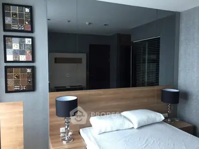 Modern bedroom with stylish decor and mirrored wall, featuring elegant bedside lamps and contemporary artwork.