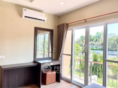 Bright bedroom with balcony access and air conditioning, featuring a stylish vanity and serene outdoor view.