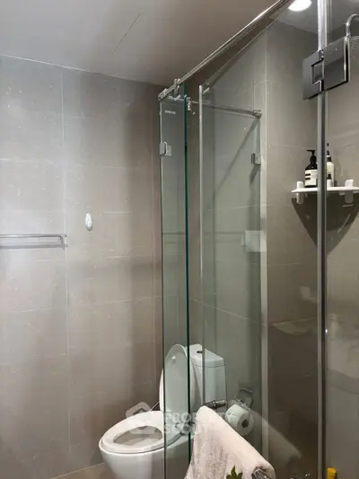 Modern bathroom with glass shower and sleek fixtures in contemporary apartment.