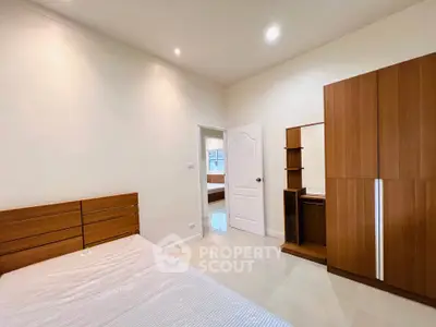 Spacious bedroom with modern wooden furniture and ample natural light.