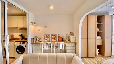 Modern open-plan living room with stylish decor and integrated kitchen featuring a washing machine.