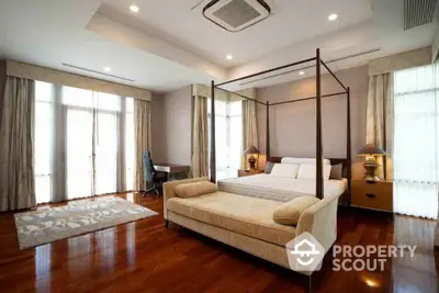 Luxurious bedroom with canopy bed and elegant decor, featuring hardwood floors and ample natural light.