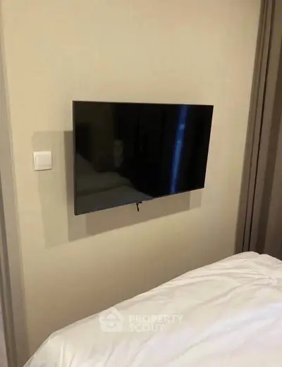 Modern bedroom with wall-mounted flat-screen TV and cozy bedding