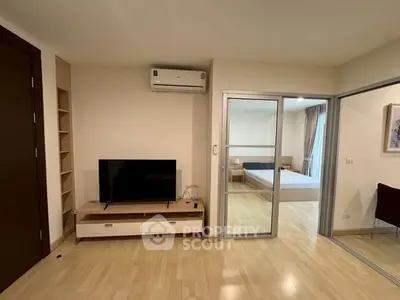 Modern apartment with open living room and bedroom, featuring sleek wooden flooring and contemporary furnishings.