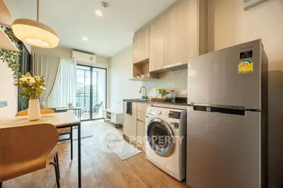 Modern kitchen with washing machine and fridge, open layout to dining area and balcony view.