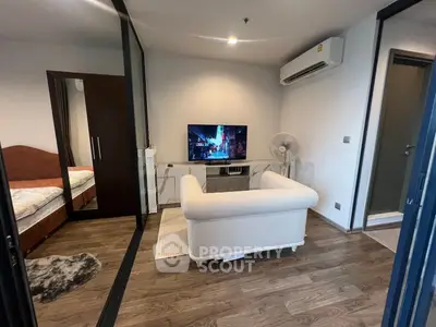 Modern living room with cozy sofa and TV, adjacent to a bedroom, featuring sleek wooden flooring and air conditioning.