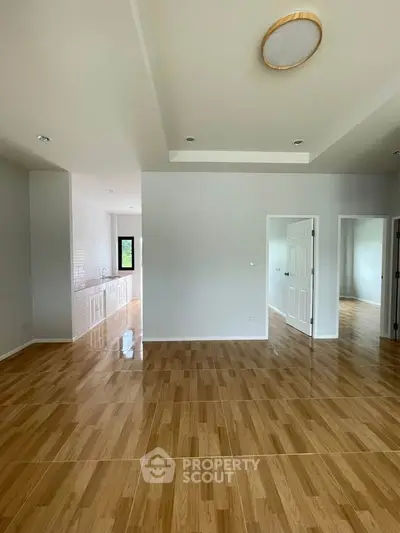 Spacious open-plan living area with wooden flooring and modern lighting, ideal for family gatherings.
