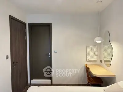 Cozy bedroom with study area featuring a wooden desk and chair, modern lighting, and a stylish mirror.