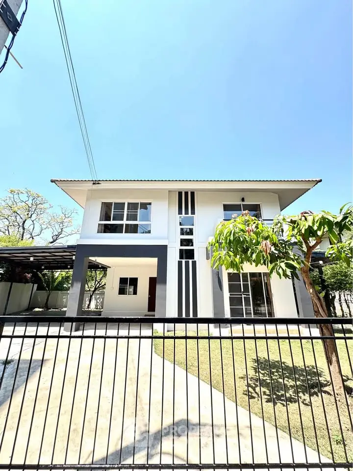 Modern two-story house with sleek design and spacious front yard under clear blue sky.