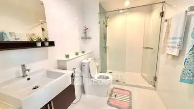 Modern bathroom with glass shower, sleek sink, and elegant decor in a bright, spacious setting.