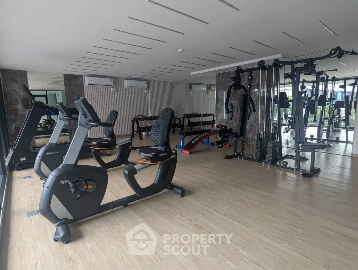 Modern gym with state-of-the-art fitness equipment and spacious layout in luxury residential building.