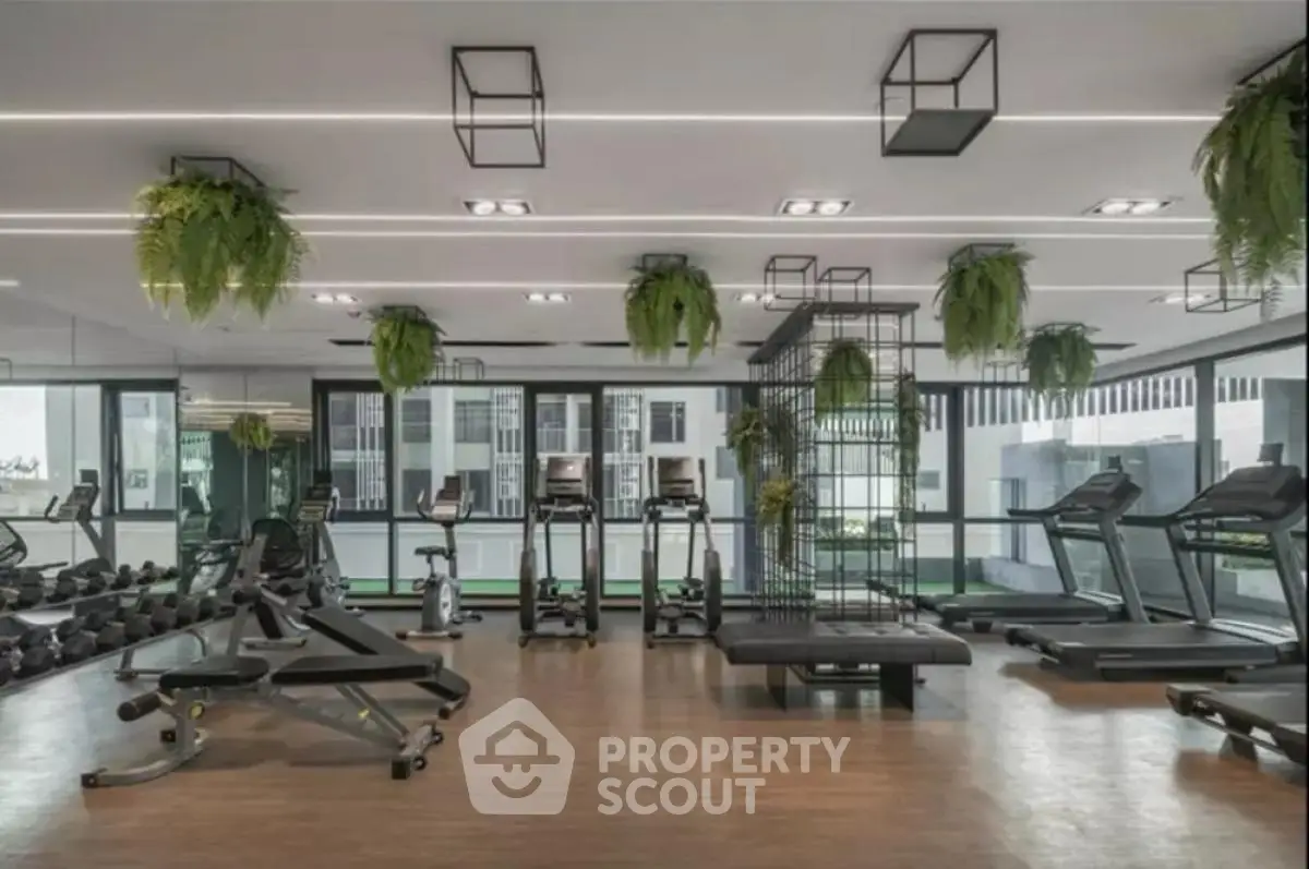 Modern gym with state-of-the-art equipment and lush greenery in luxury apartment complex.
