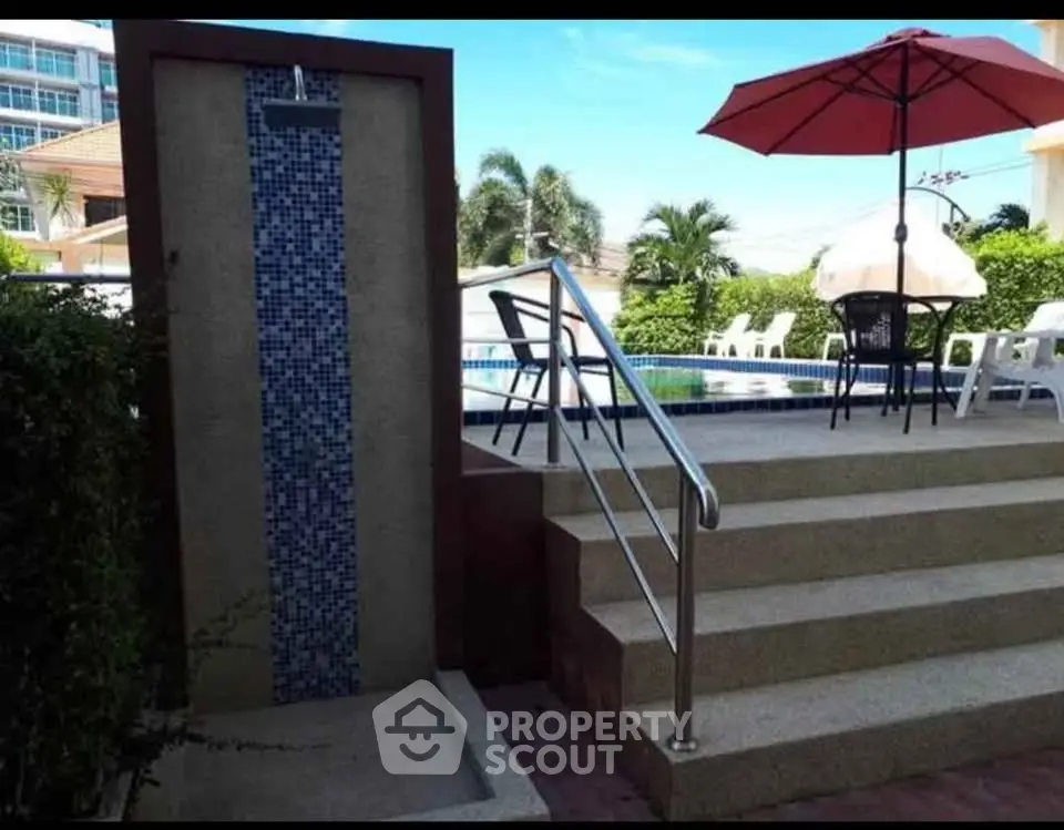 Luxurious poolside area with outdoor shower and seating, perfect for relaxation and leisure.