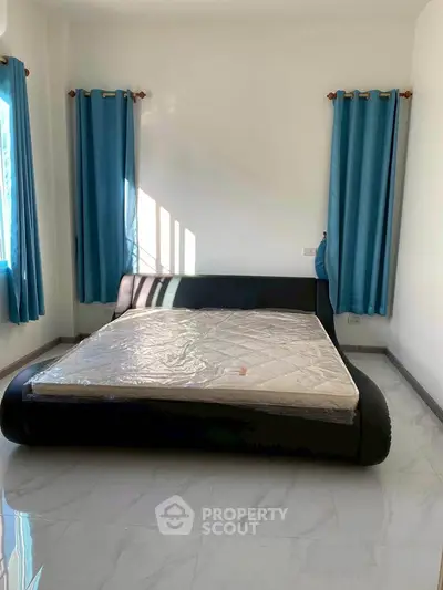 Spacious bedroom with modern bed and blue curtains, perfect for relaxation.