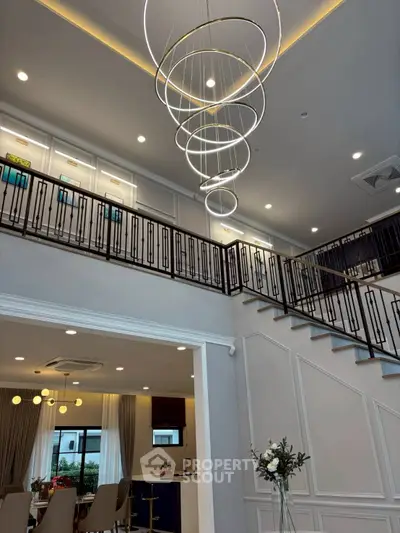 Luxurious modern interior with elegant staircase and stunning chandelier in a spacious living area.