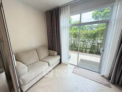 Cozy living room with large window and garden view, featuring a comfortable sofa and elegant curtains.