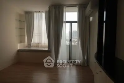 Spacious living room with large windows and city view, featuring elegant curtains and built-in shelves.