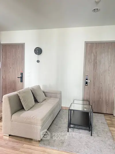 Modern living room with stylish beige sofa and glass coffee table on wooden flooring.