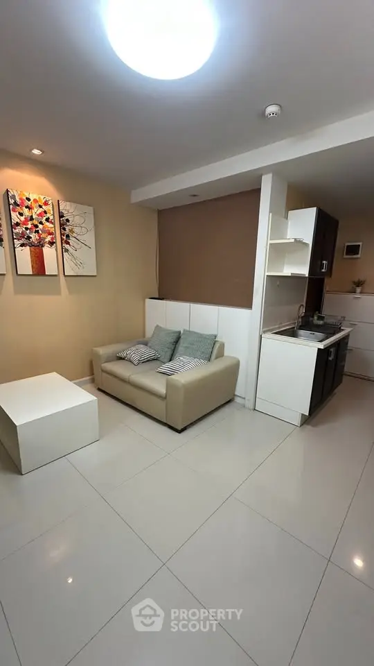 Modern compact living room with kitchenette, featuring sleek design and cozy seating area.