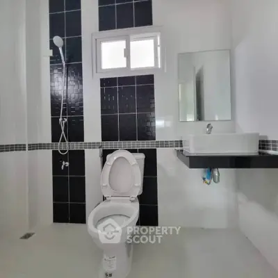 Modern bathroom with sleek black and white tiles, featuring a shower and contemporary fixtures.