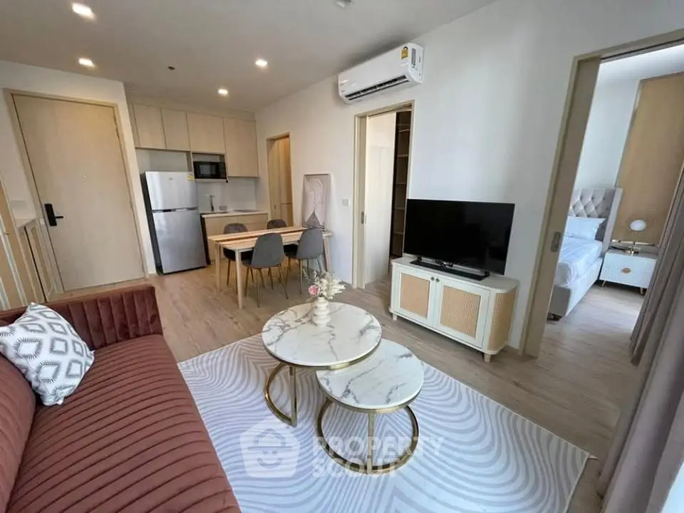 Modern open-plan living room with stylish furniture and kitchen area in a cozy apartment.