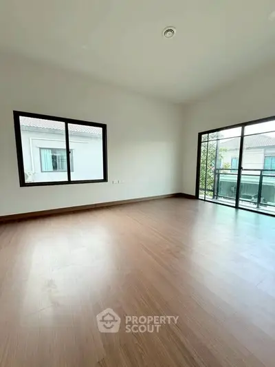 Spacious empty room with large windows and wooden flooring, perfect for customization.