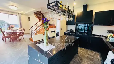 Luxurious open-plan kitchen and dining area with modern black cabinetry and elegant staircase.