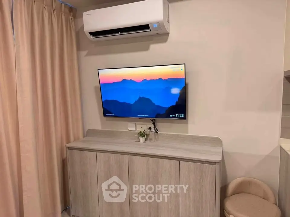 Modern living room with wall-mounted TV and air conditioning unit, featuring stylish cabinetry and neutral decor.
