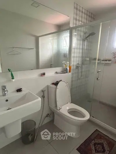 Modern bathroom with glass shower, sink, and toilet in sleek design.