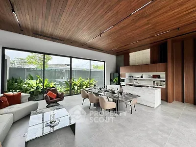 Luxurious open-plan living and dining area with modern furnishings and large windows overlooking greenery.
