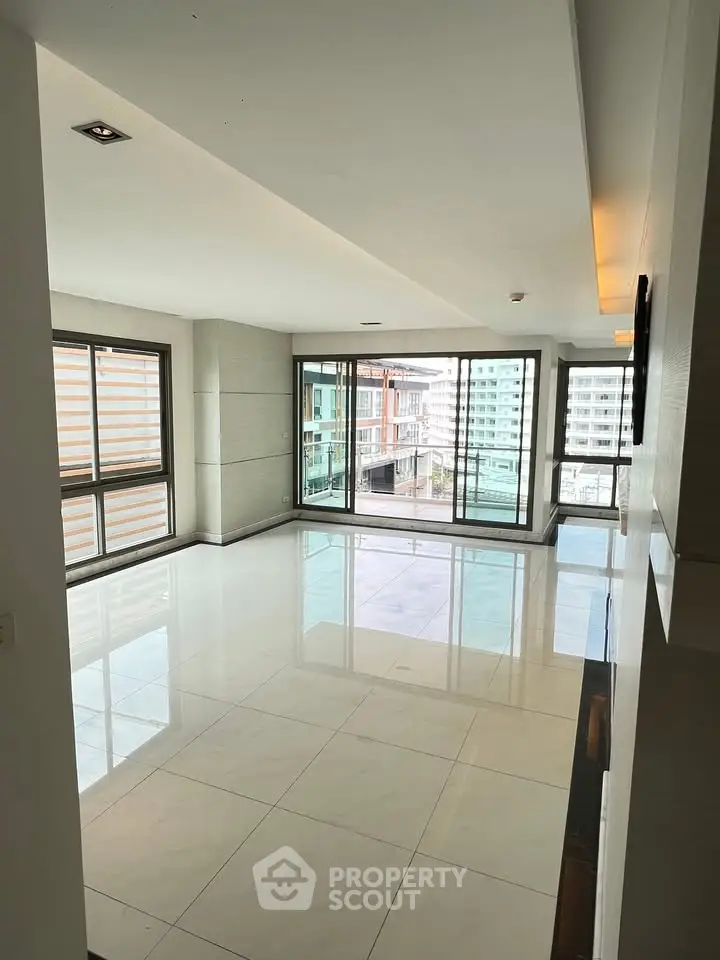 Spacious modern living room with large windows and city view, perfect for urban living.